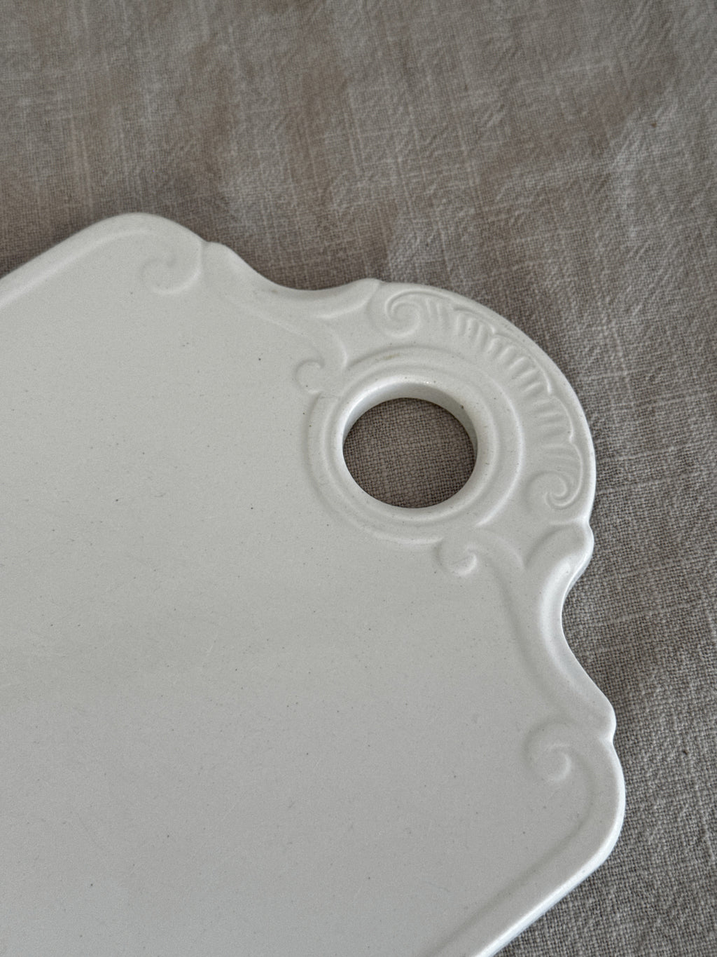 Close-up of the moulded shell and C-scroll relief around the hanging hole of the faience board