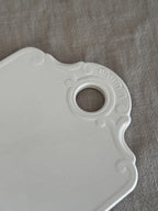 Close-up of the moulded shell and C-scroll relief around the hanging hole of the faience board