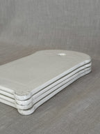 Four white faience boards stacked, showing the thickness of the earthenware and the moulded edge