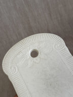Detail of the leaf palmette relief around the hanging hole on a white faience board
