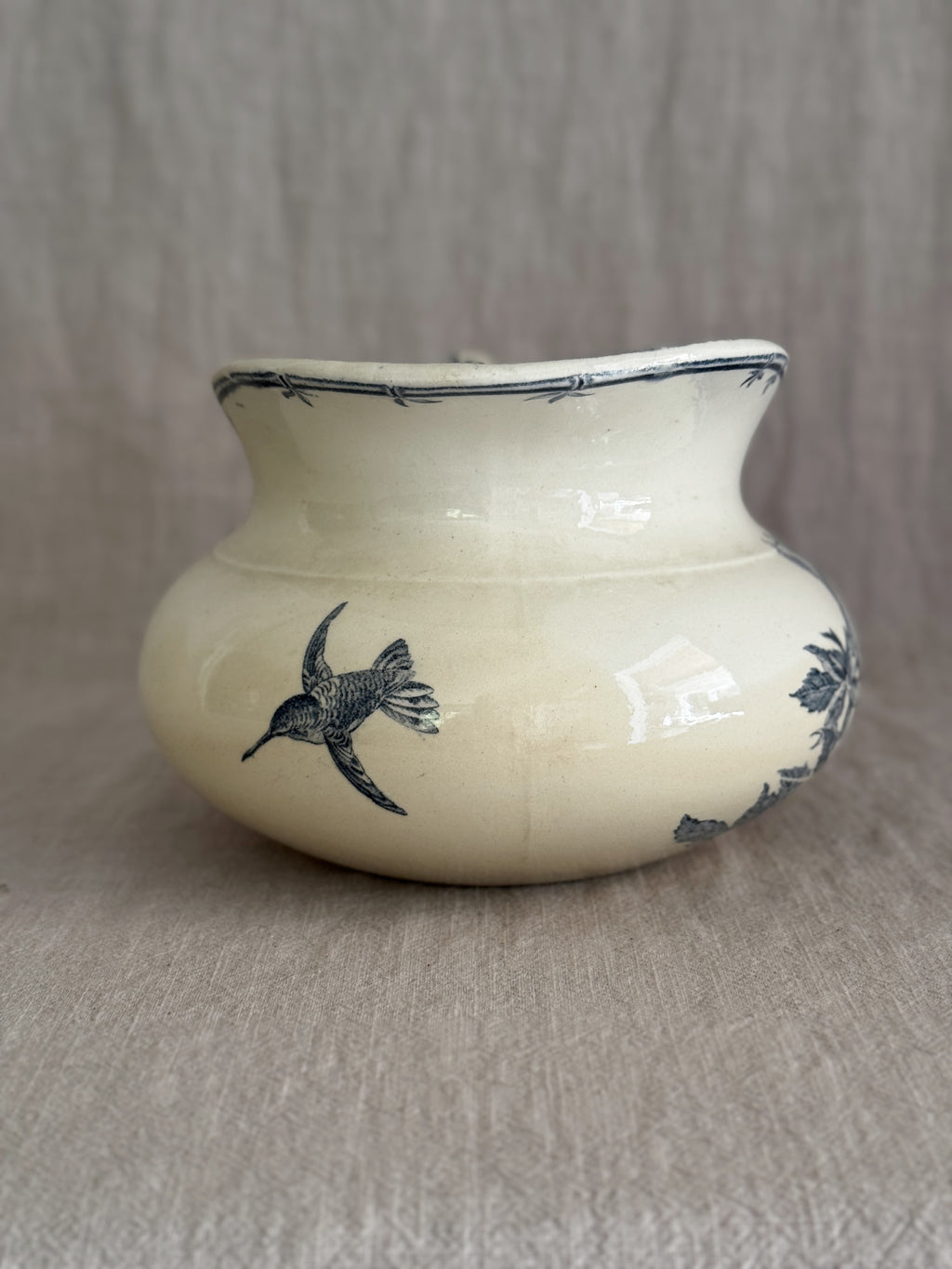 The reverse of the jug showing a printed blue hummingbird in flight and a slender bamboo spray on the crazed cream glaze