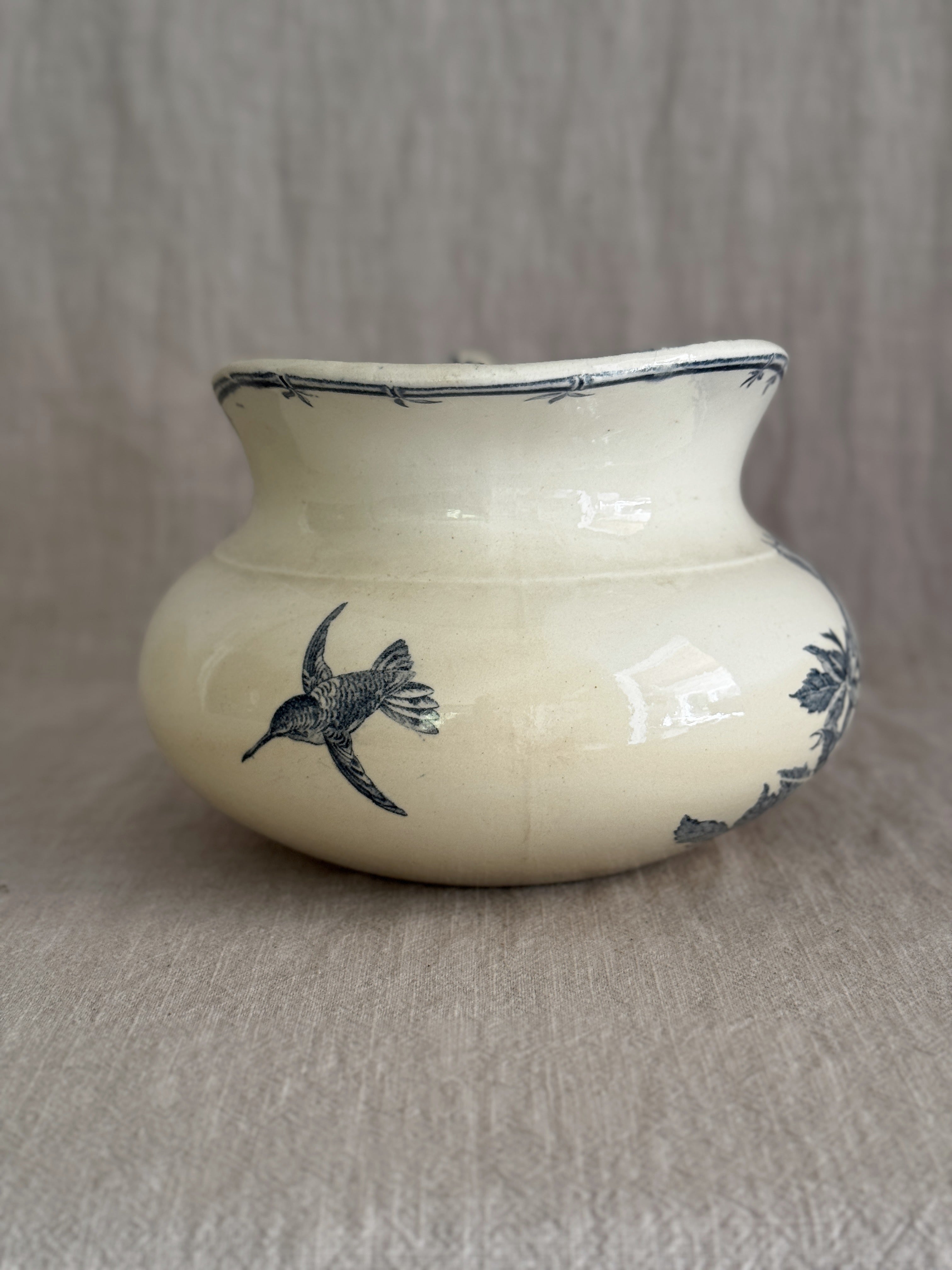 The reverse of the jug showing a printed blue hummingbird in flight and a slender bamboo spray on the crazed cream glaze