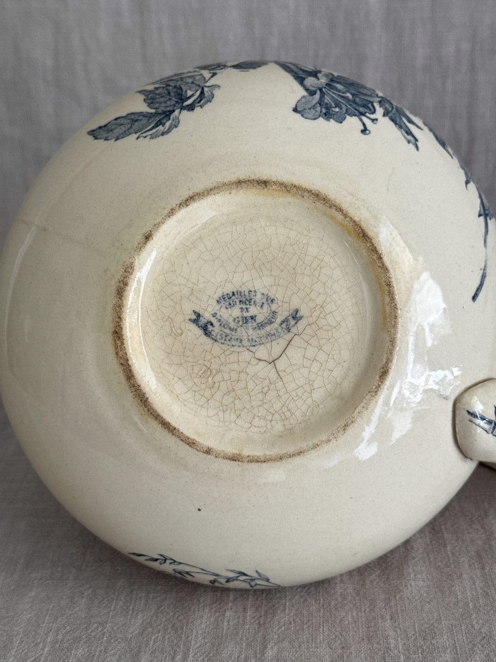 Underside of the jug showing the printed blue oval Gien mark reading Medailles d'Or, Faiencerie de Gien, on the finely crazed cream glaze