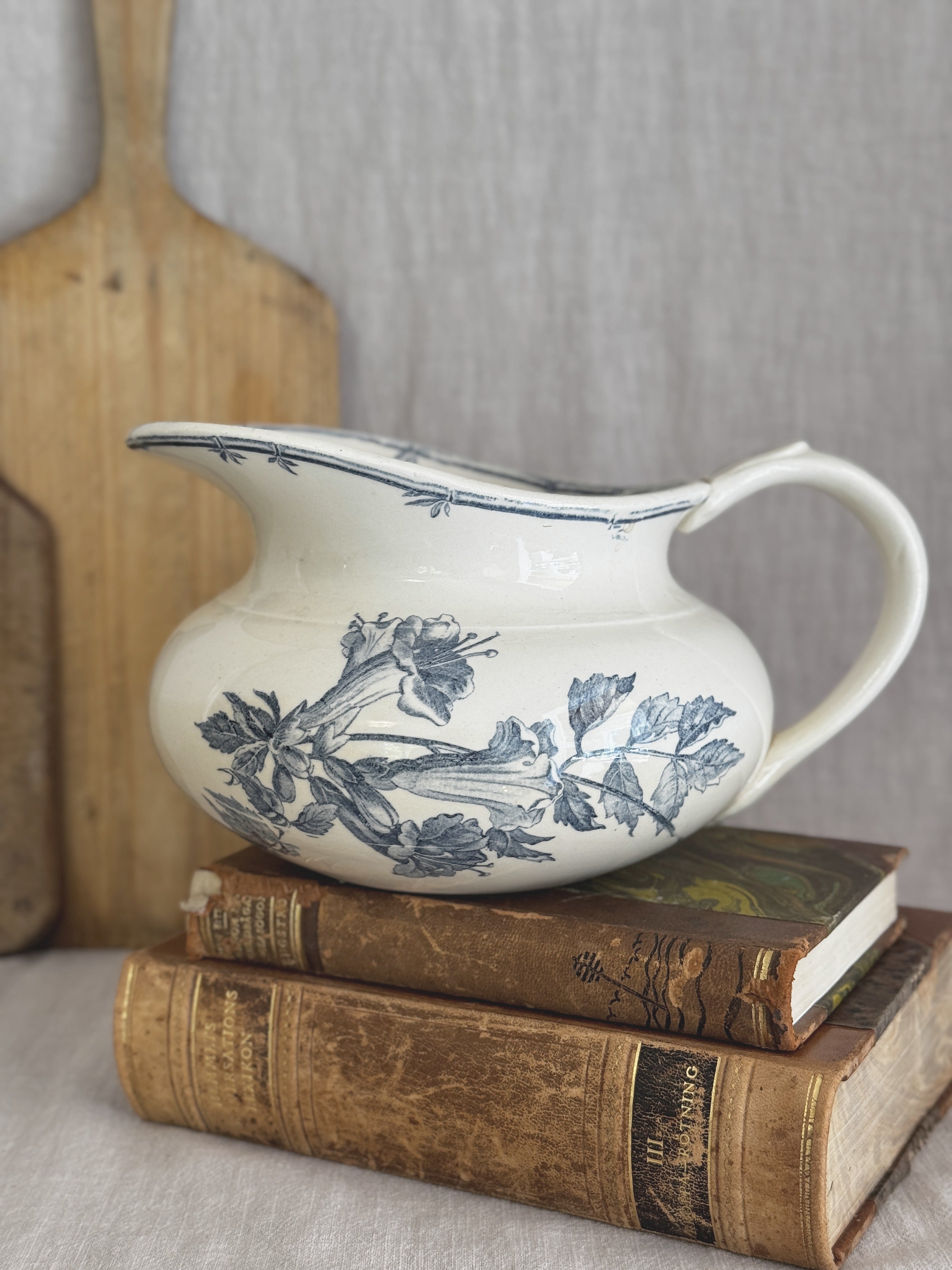 Gien faience jug with blue-grey trumpet flowers, styled on antique books