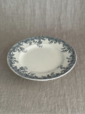 Low cream ironstone compotier with a blue-grey rose and trellis transfer border, seen at an angle on a linen cloth
