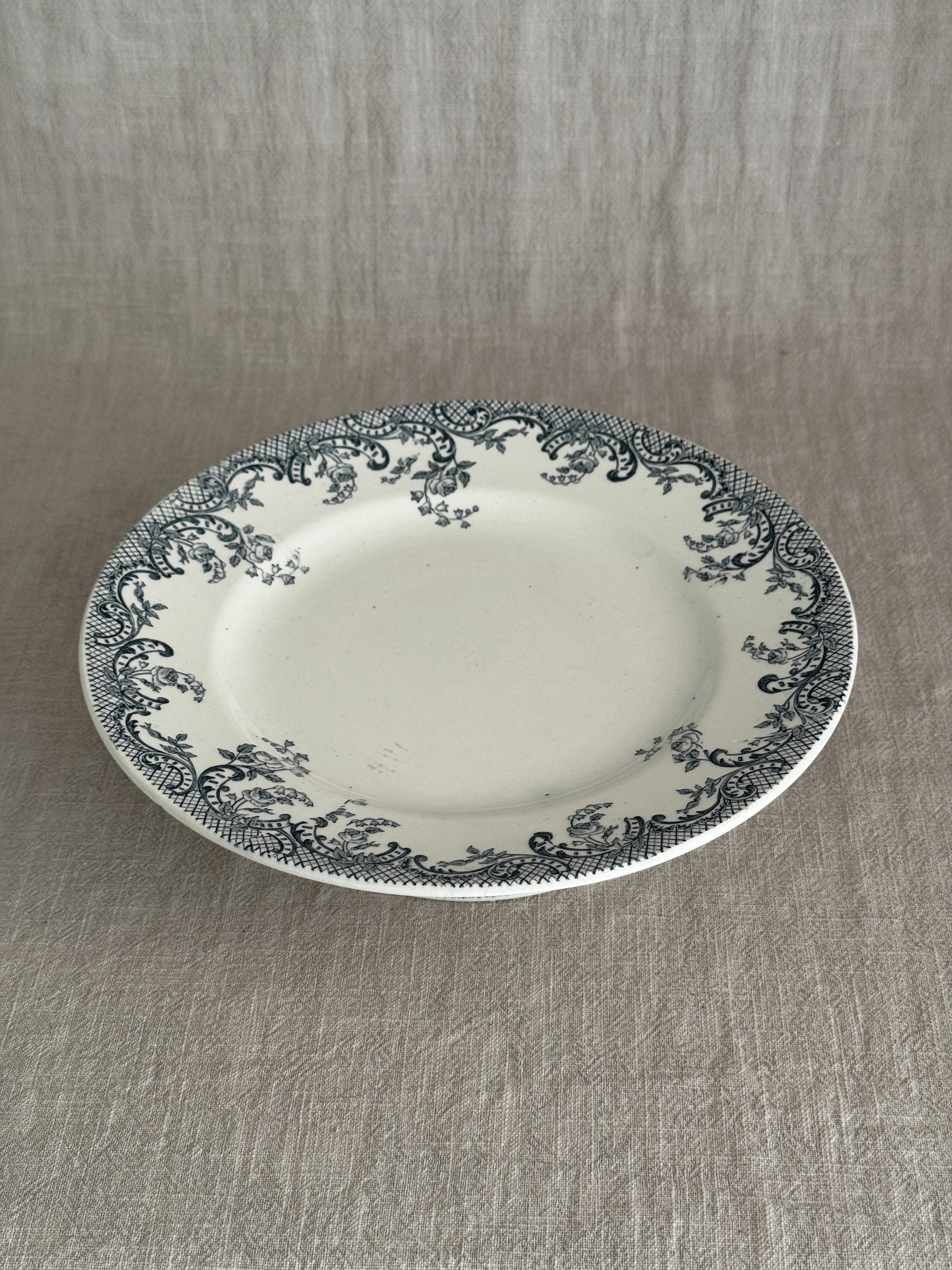 Low cream ironstone compotier with a blue-grey rose and trellis transfer border, seen at an angle on a linen cloth