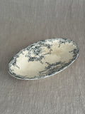 Antique Belgian oval faience ravier dish with deep teal rococo transfer print and warm tea staining, on a linen cloth