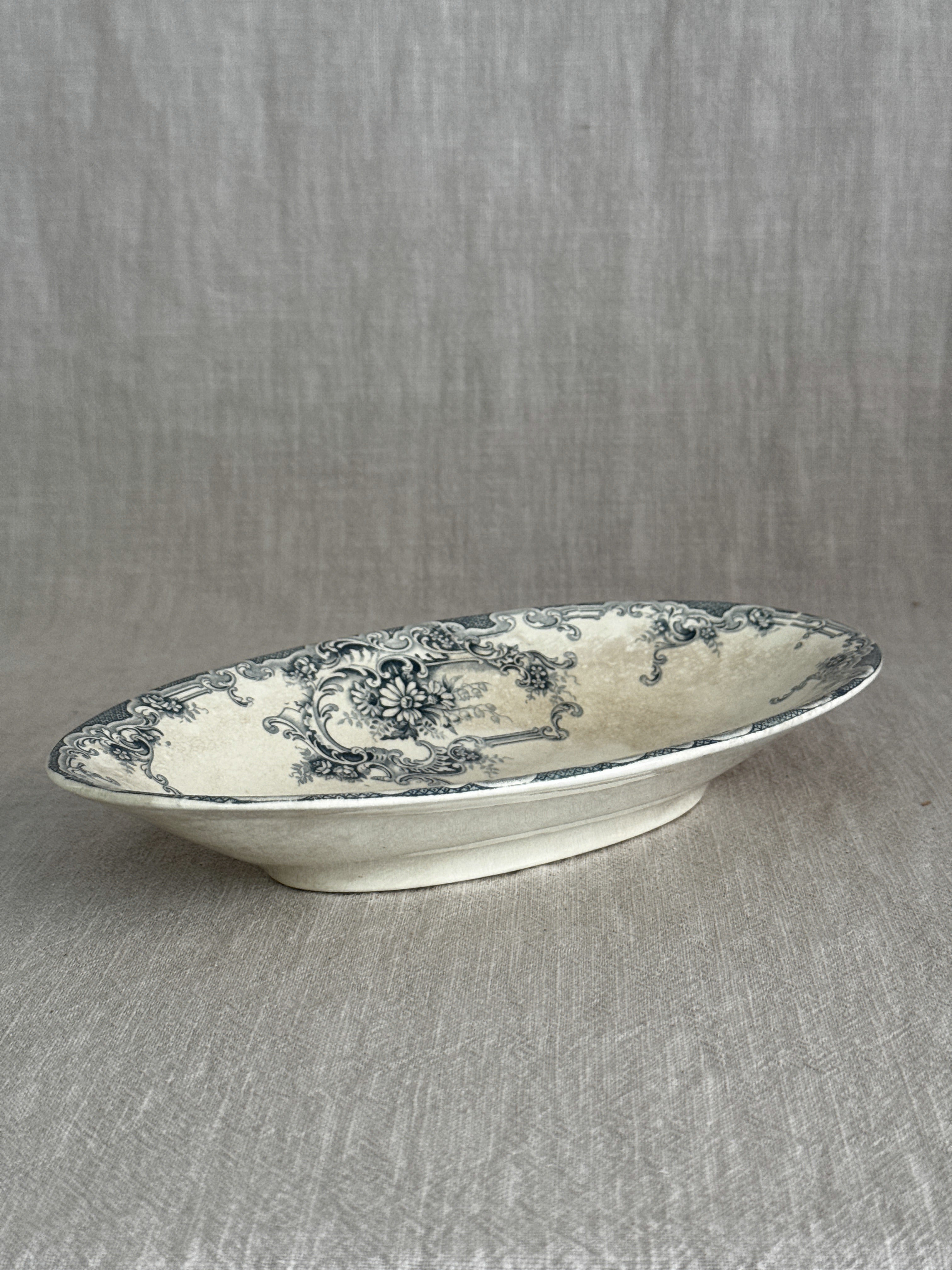 Side view of the oval ravier showing its shallow depth, wavy rim and plain cream underside
