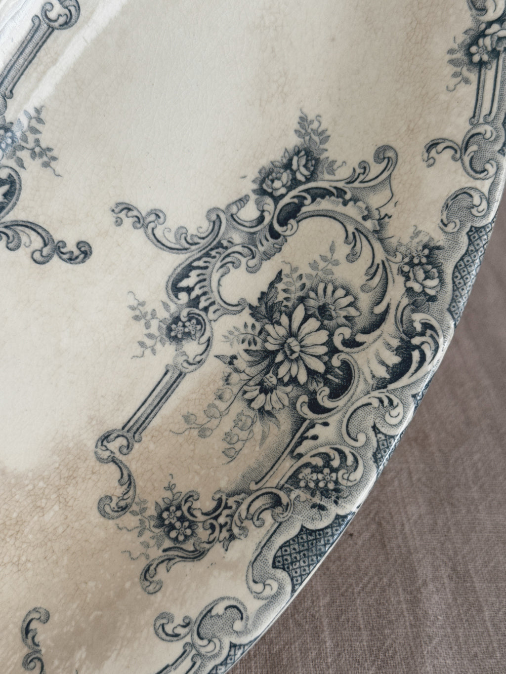 Close-up of the teal transfer print - a daisy bouquet inside a rococo cartouche beside a lattice panel