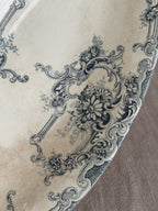 Close-up of the teal transfer print - a daisy bouquet inside a rococo cartouche beside a lattice panel