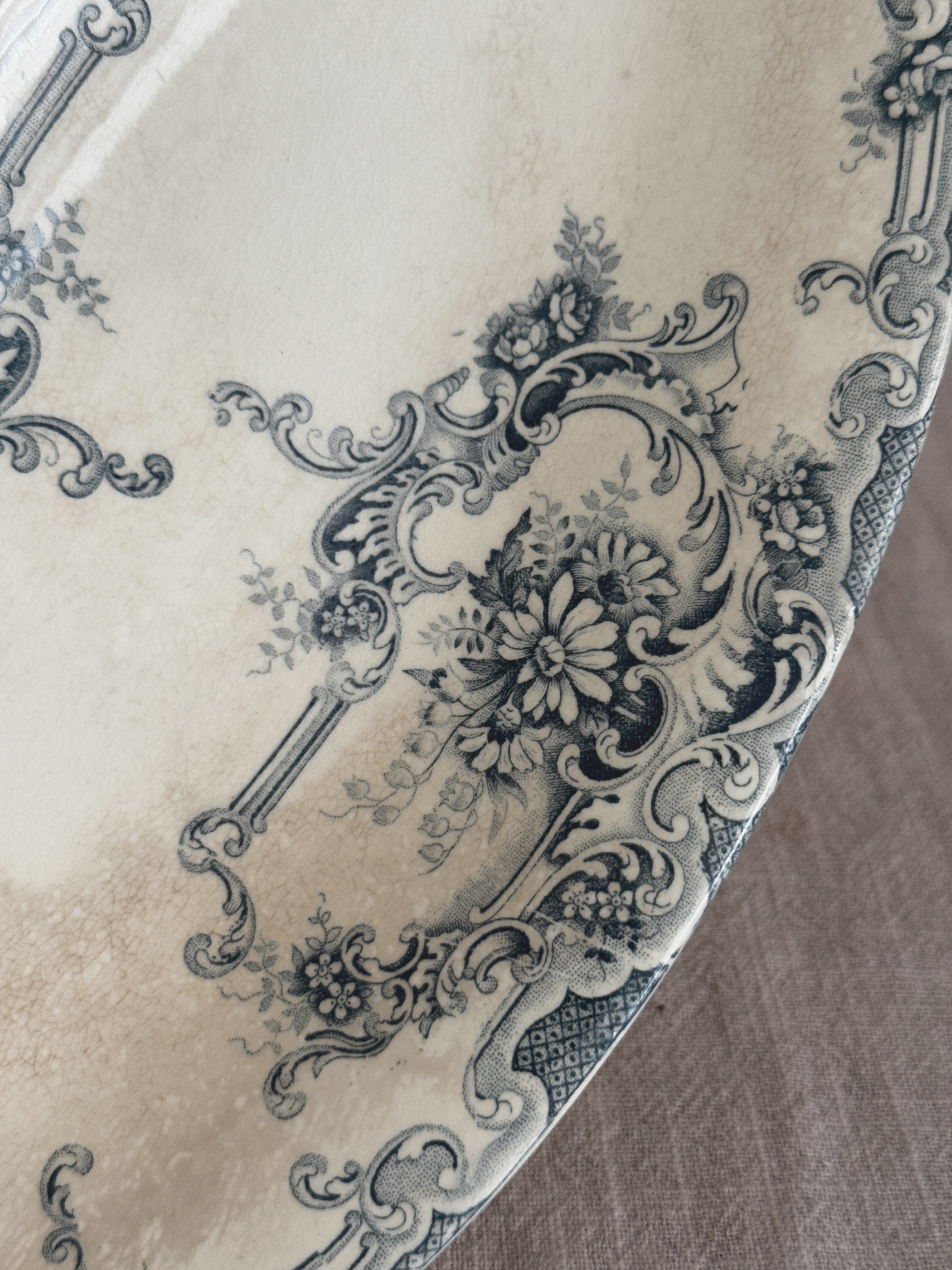 Close-up of the teal transfer print - a daisy bouquet inside a rococo cartouche beside a lattice panel