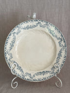 A single Longwy plate upright on a white stand, showing the full teal garland border and the moulded swirl in the well