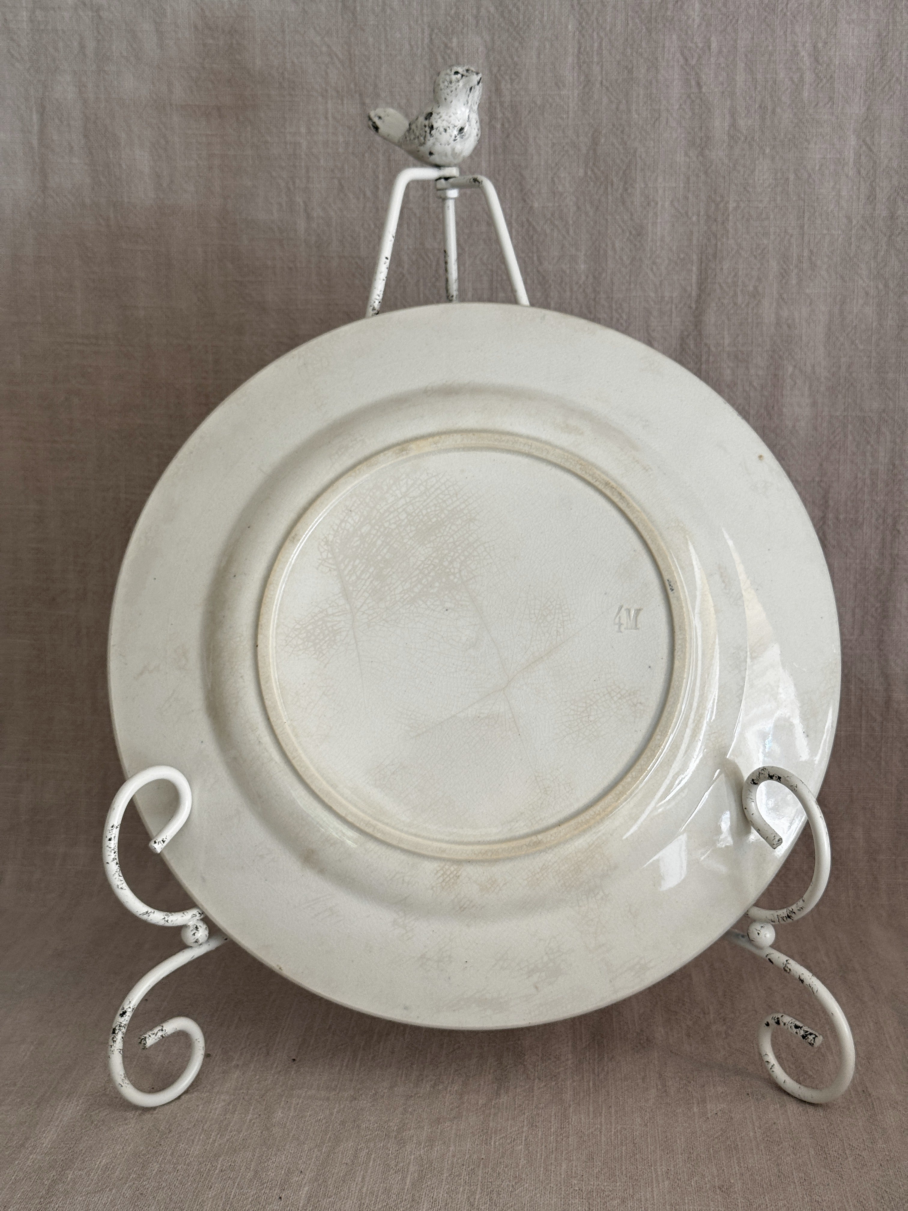 Reverse of an unmarked cream terre de fer luncheon plate showing the foot ring, fine glaze crazing and an impressed 4M mould number