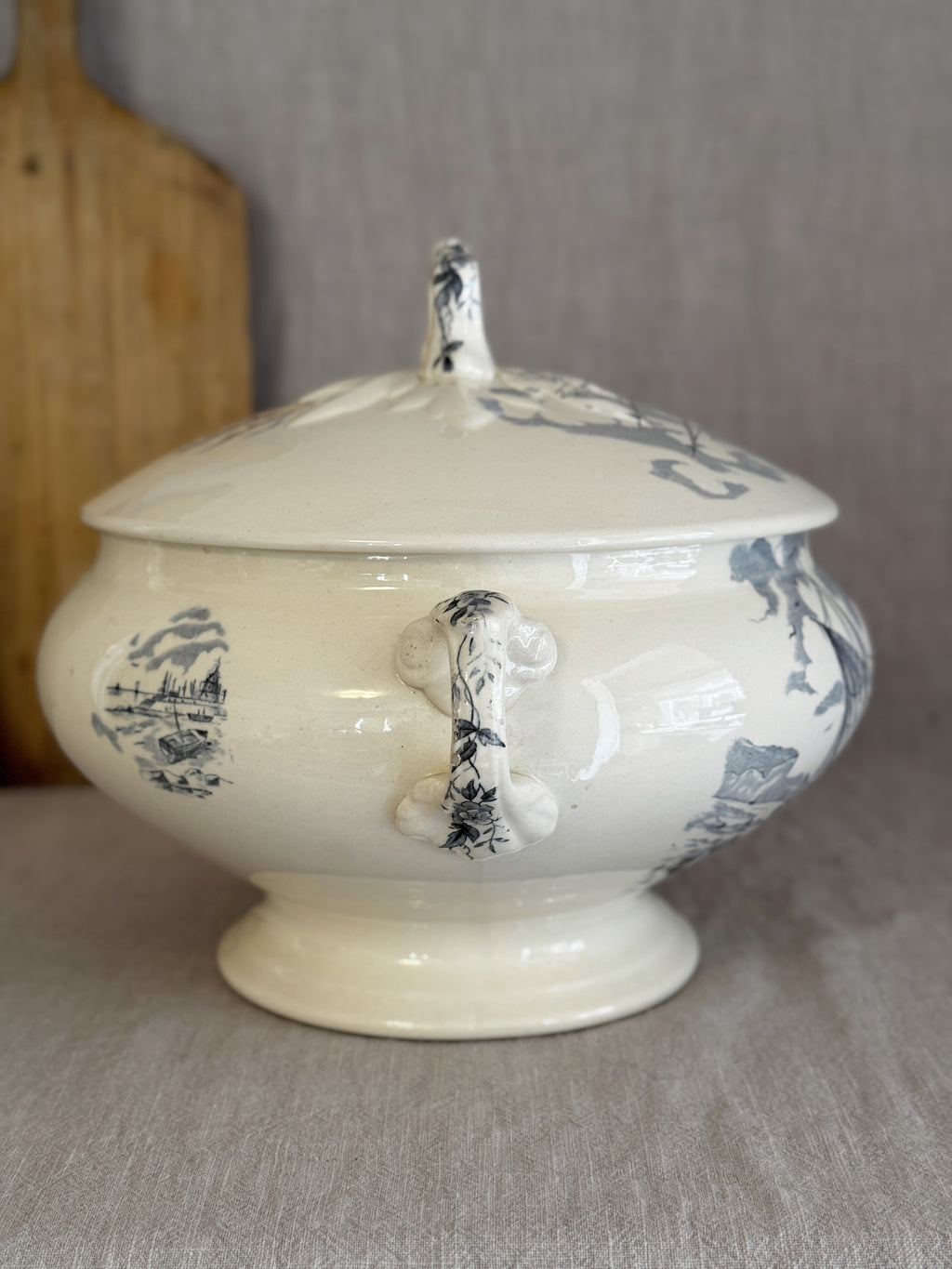 Side view of the antique French tureen showing the ribbon-loop handle with its hand-brushed floral sprig