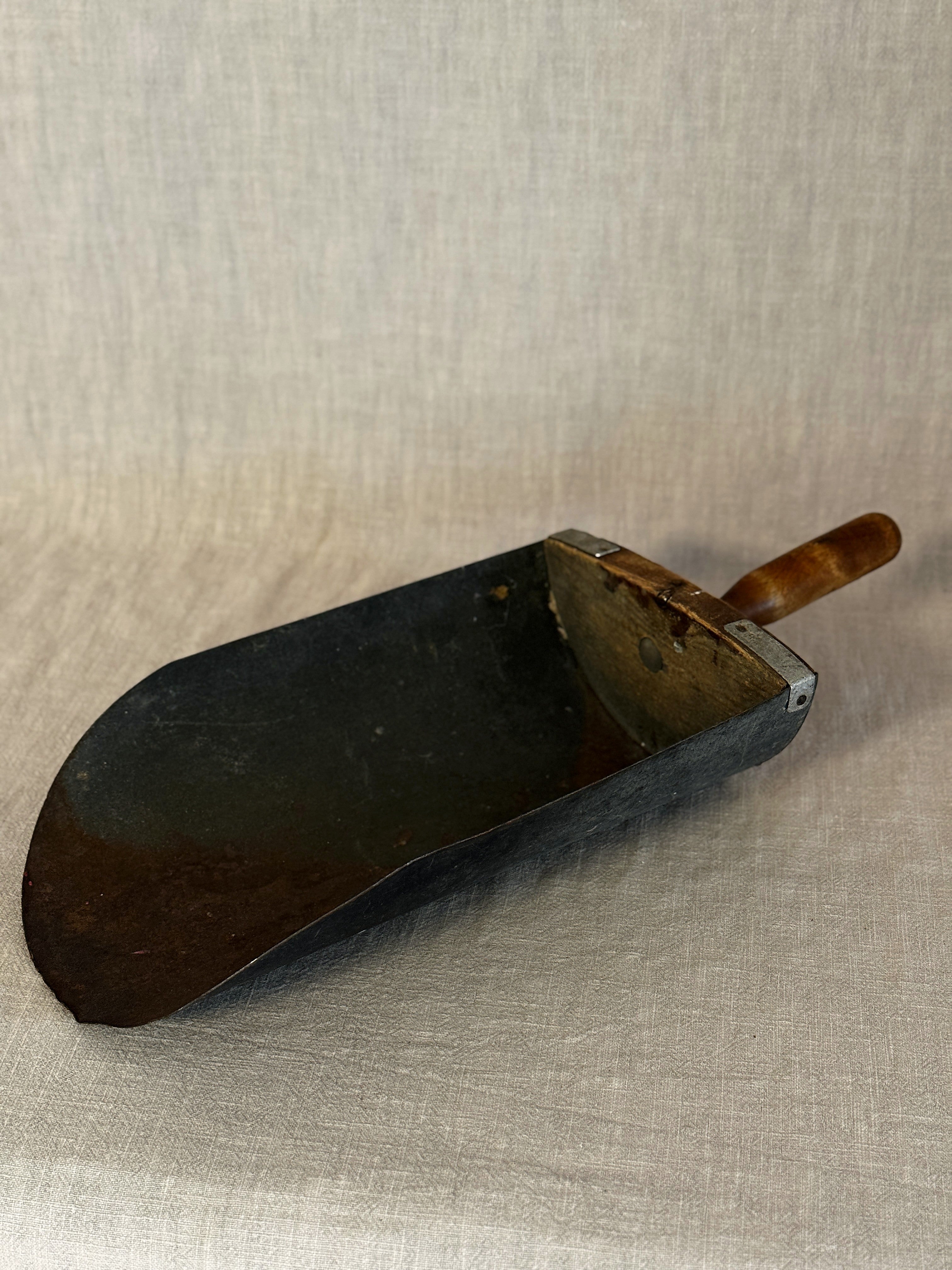 Close-up of the grain scoop blade showing the dark patina and rust marks