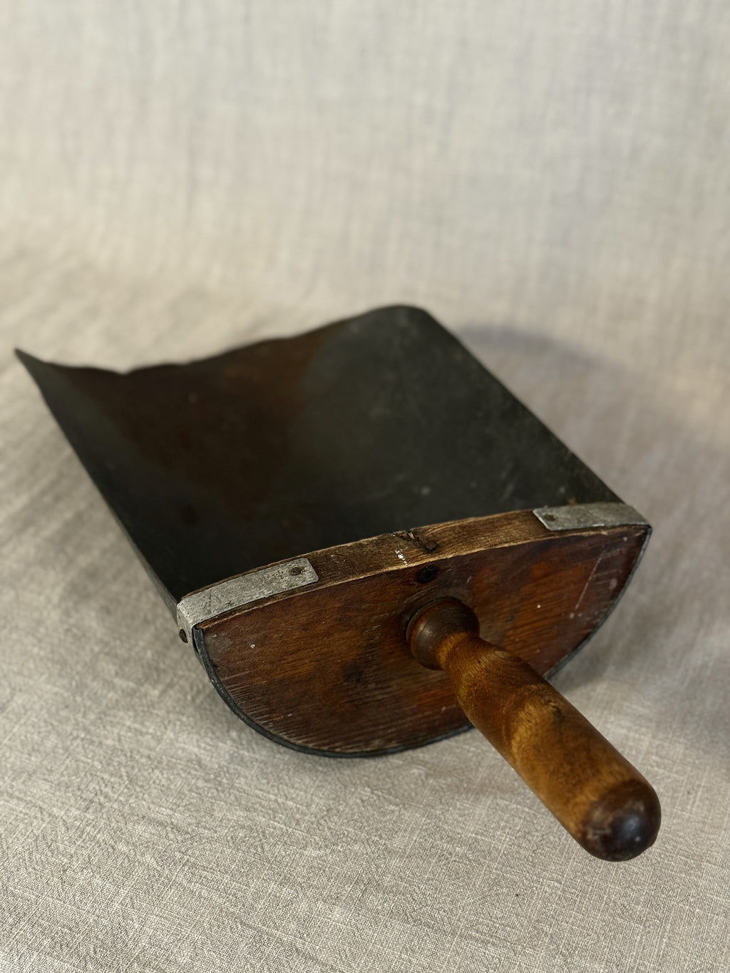 Three-quarter view of the Swedish grain scoop with its shaped wooden back, iron straps and turned handle