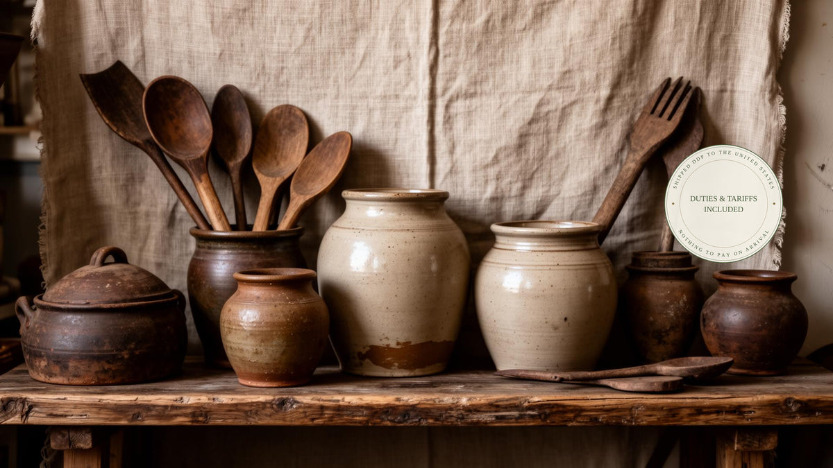 French and Swedish farmhouse antiques — wooden spoons and stoneware crocks on linen, with a seal reading duties and tariffs included, shipped DDP to the United States